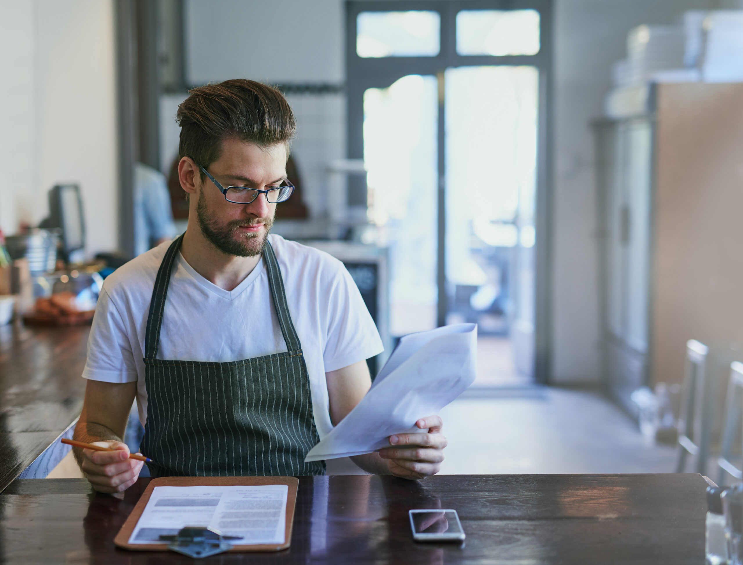 A restaurant manager analyzing labor costs and menu profitability in a commercial kitchen setting.